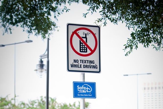A road sign on Walt Disney World property discourages drivers, especially cast members, from texting while driving.